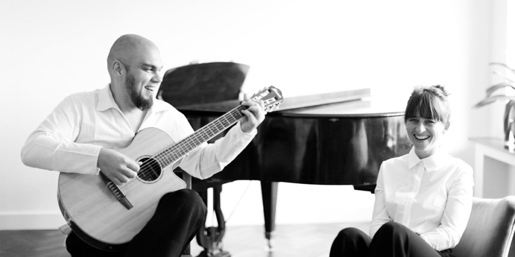 Wellington Barros an der Gitarre und Anne Bontems lachend vor einem Klavier