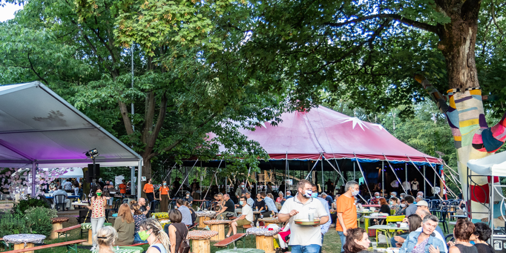 Das Zelt in dem das Weltmusikfest und Haaste Töne jedes Jahr stattfindet. Festivalbesucher mit Maske.