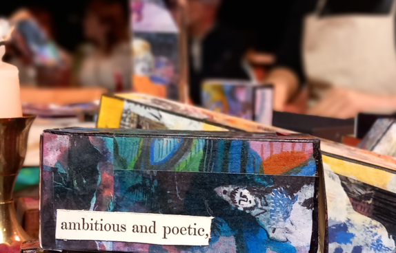 Eine Kerze und ein Buch mit einem bemalten und beschrifteten Buchdeckel.