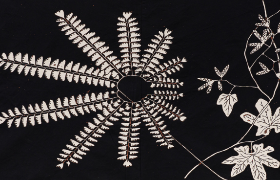 Ein gesticktes/ gewebtes Kunstwerk des Künstlers. Zu sehen sind eine große und mehrere kleine Blumenblüten auf schwarzem Samt.