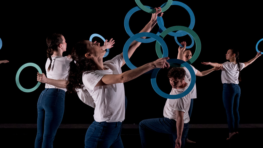 Mehrere Tänzer der Compagnie Gandini Juggling jonglieren mit blauen Reifen