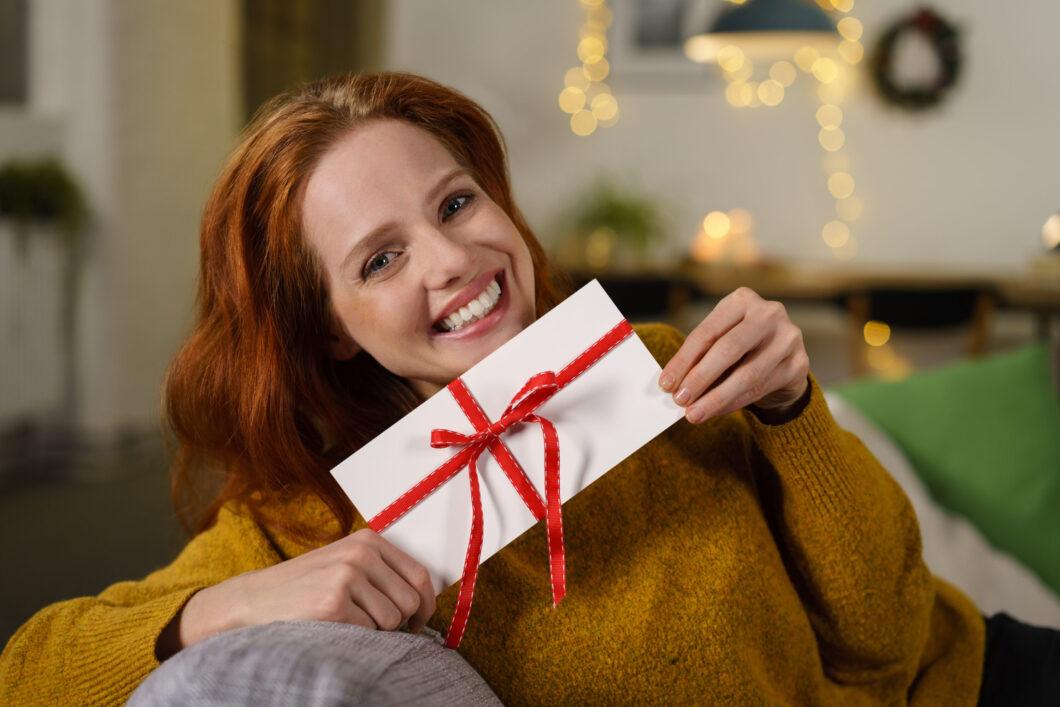 Attractive,Smiling,Woman,Holding,A,Gift,Envelope,Tied,With,A