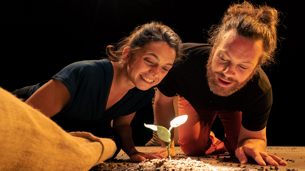 Eine Schauspielerin und ein Schauspieler beobachten eine Pflanze