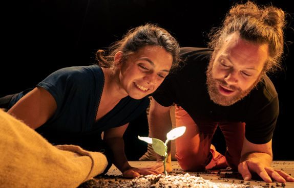 Eine Schauspielerin und ein Schauspieler beobachten eine Pflanze