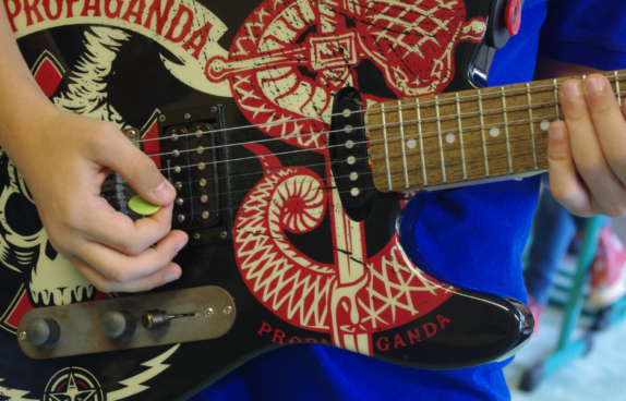 Foto für den Bandworkshop im Rahmen der Sommerwerkstatt 2026. Ein Kind spielt Gitarre.
